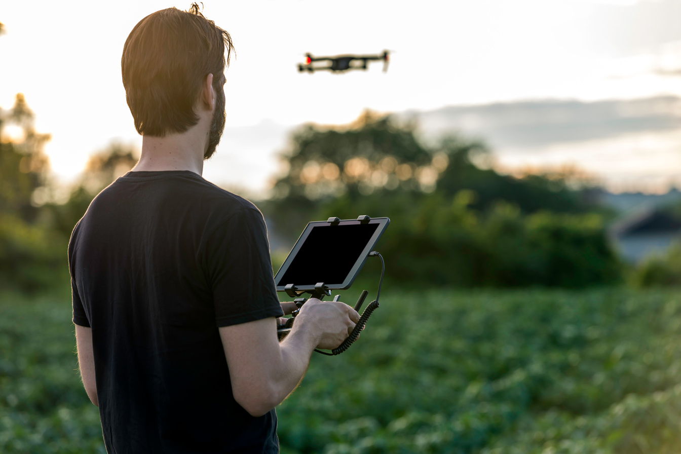 Man Pilot Using Drone Remote Controller at Sunset